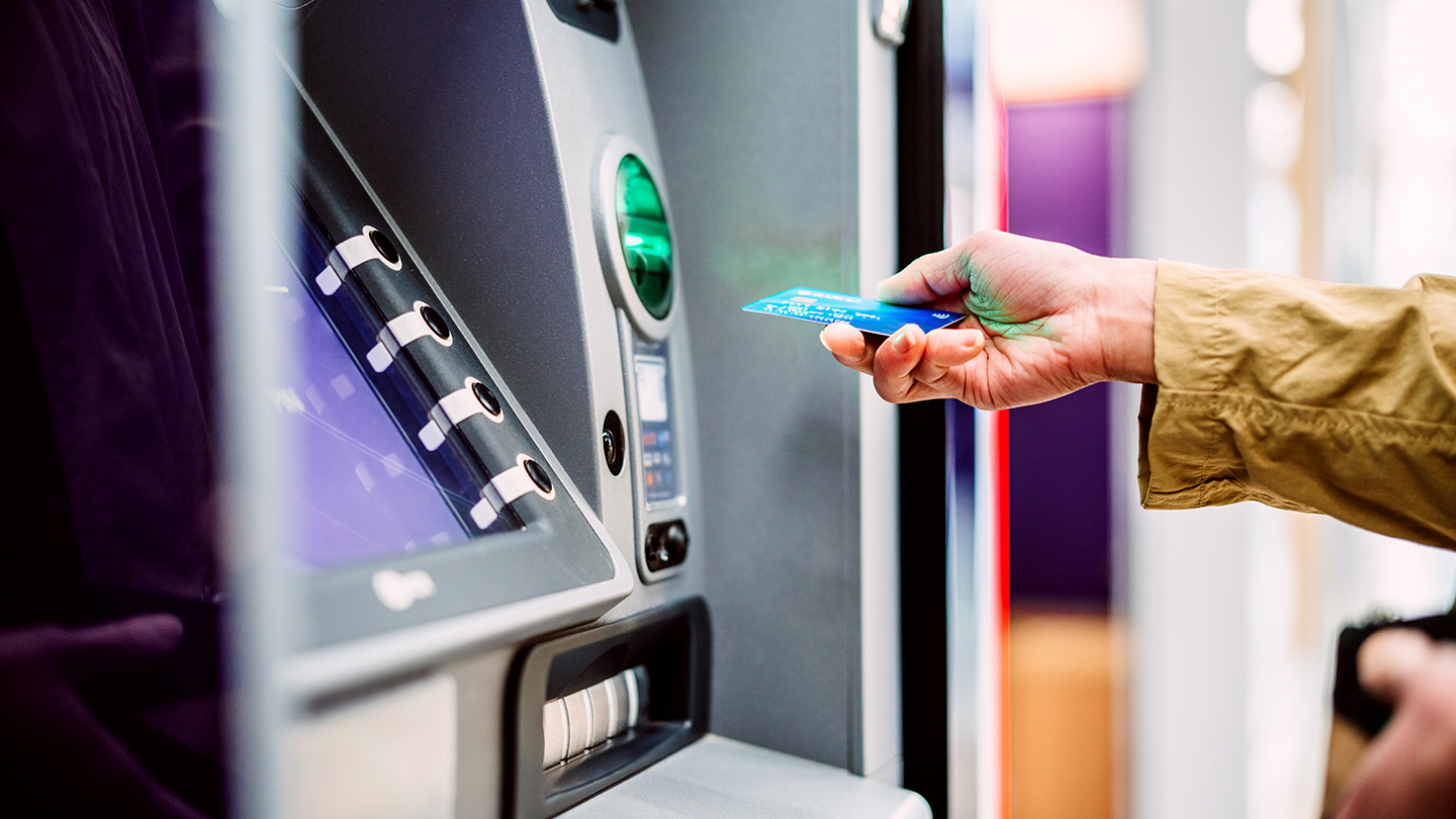 Hand inserting a card into an ATM machine.