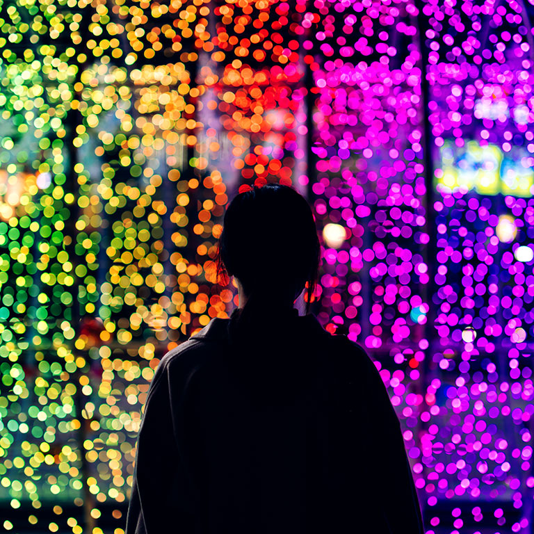 Silhouette of a person facing a multicolored light wall