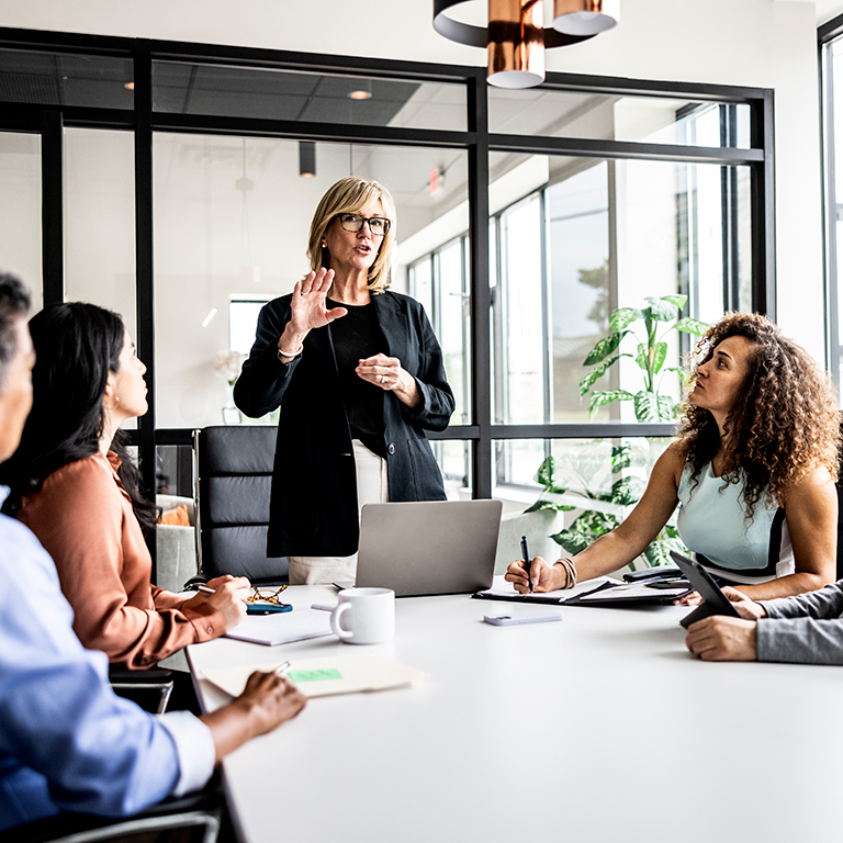 A business leader presenting to a team in a conference room during a strategic workforce planning meeting.