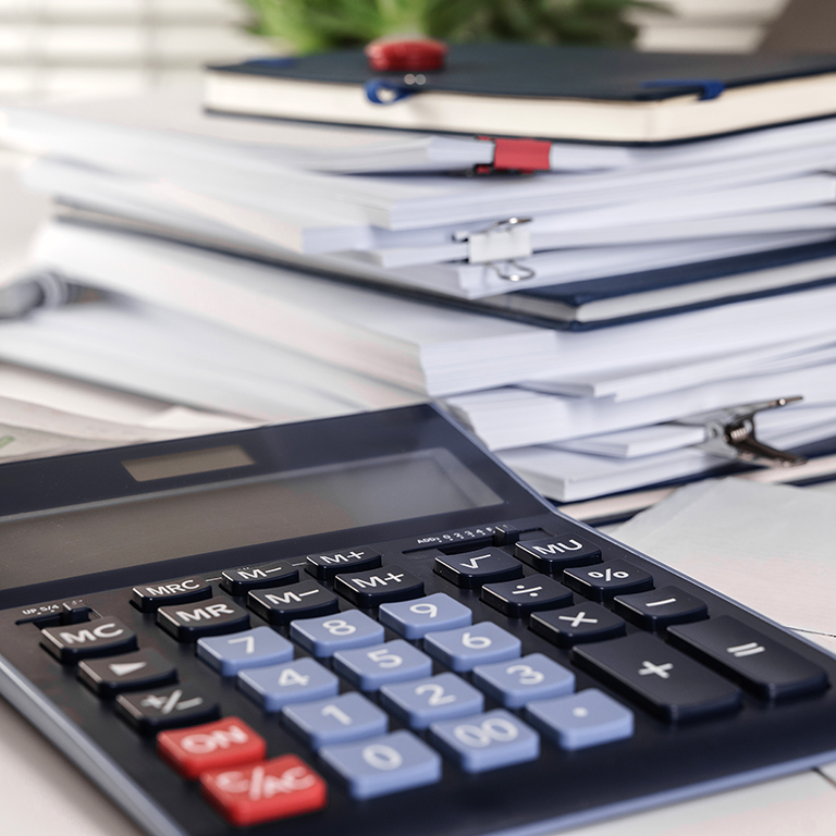A calculator shown in front of a stack of papers